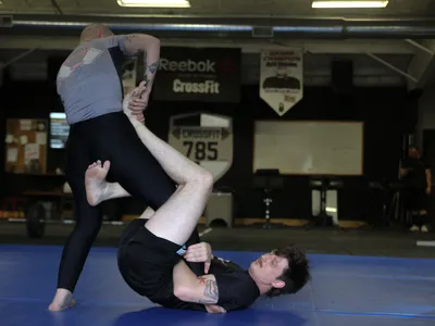 A member on their back controlling a standing partner&rsquo;s leg.