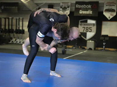 One member lifting a training partner off the mat during a takedown.