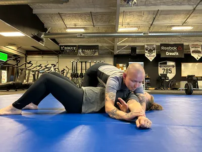 Two members drilling a pin on the mat while a third watches from the side.